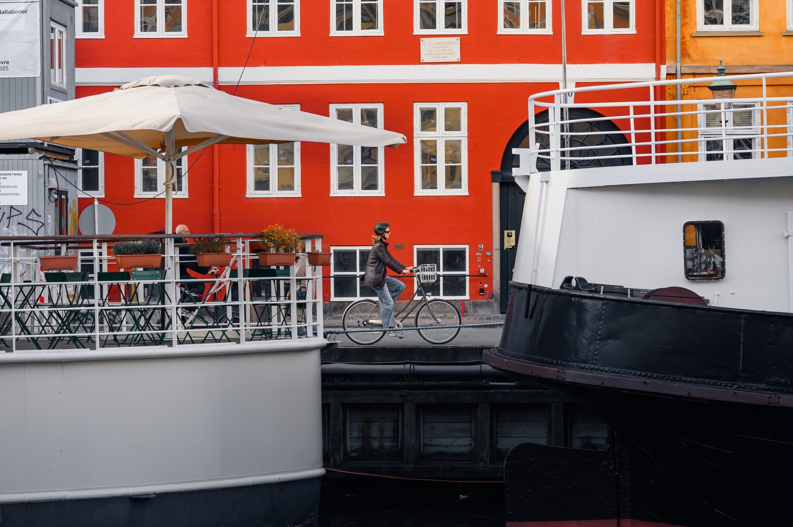 Two orange hire bikes propped beside the water at sunset, with Copenhagen townhouses on the far bank