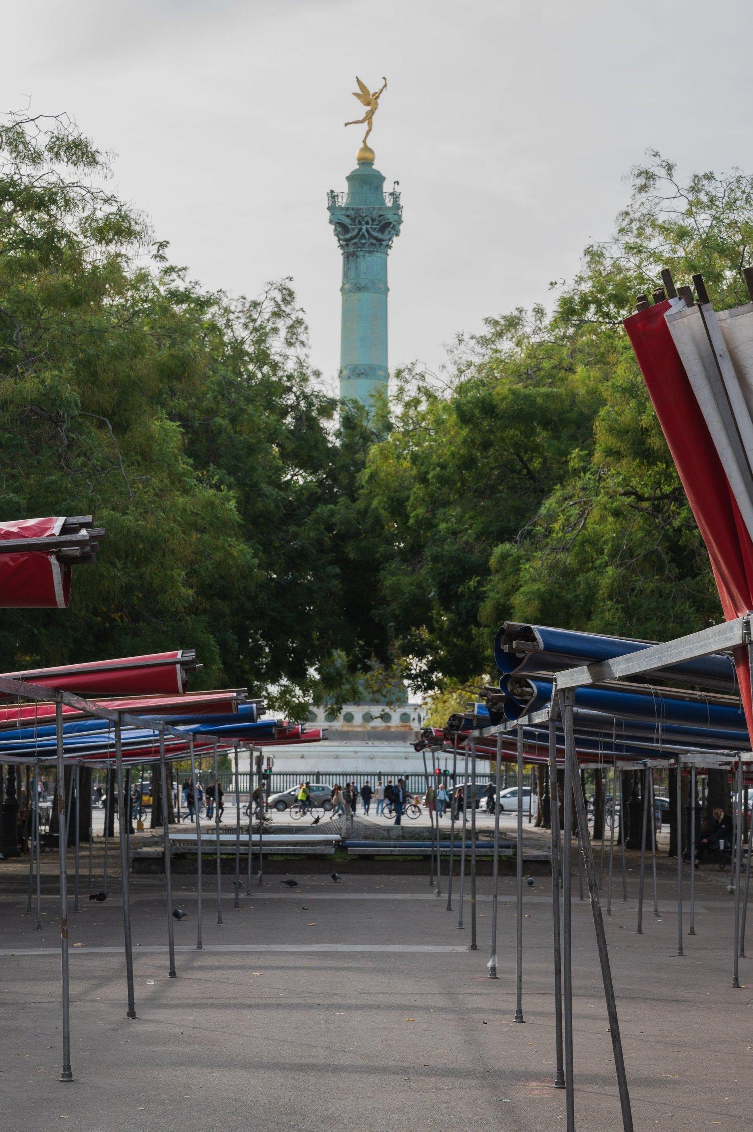 The July Column at Place de la Bastille seen down an avenue of empty market stall frames with their canopies folded