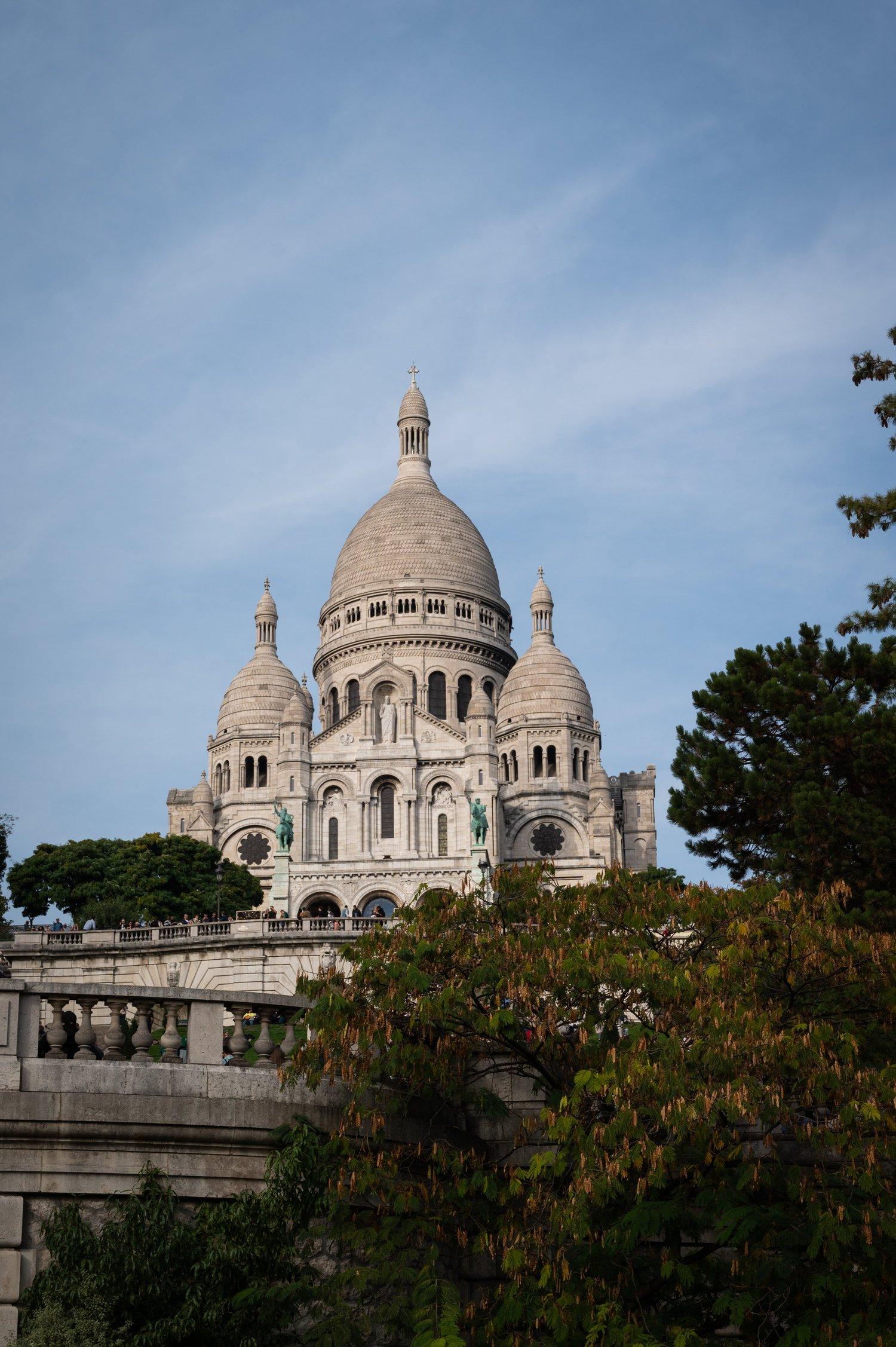 The white domes of the Sacré-Cœur above the trees, seen from the balustrade on the way up the Montmartre hill